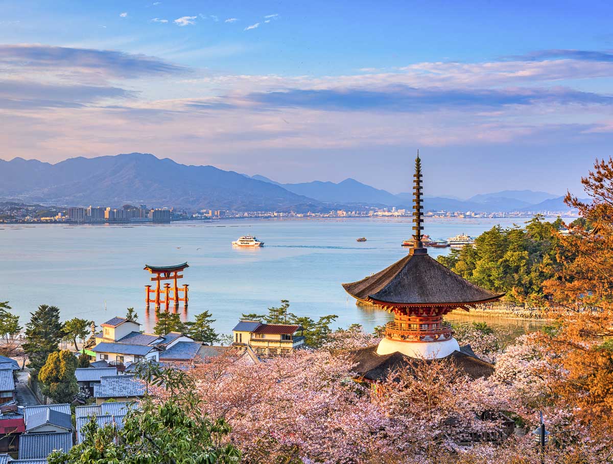 Vista da Ilha de Miyajima com pagode, cerejeiras e o torii ao fundo.