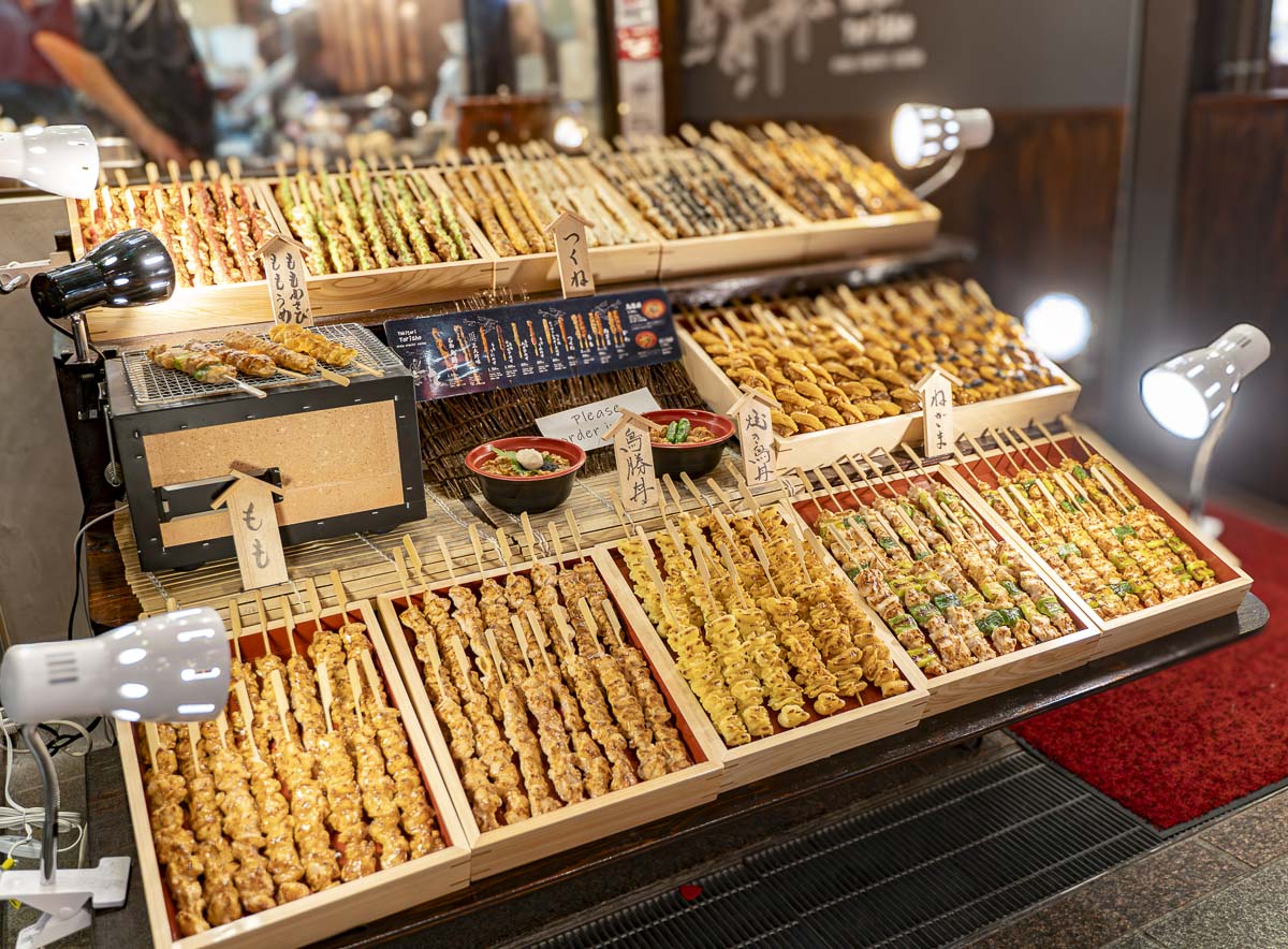 Bancas de comida japonesa no Nishiki Market, em Kyoto, com espetinhos e pratos típicos.