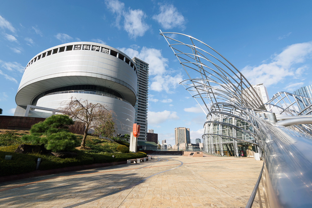 Museu Nacional de Arte de Osaka com edifício cilíndrico e estrutura metálica moderna ao lado.