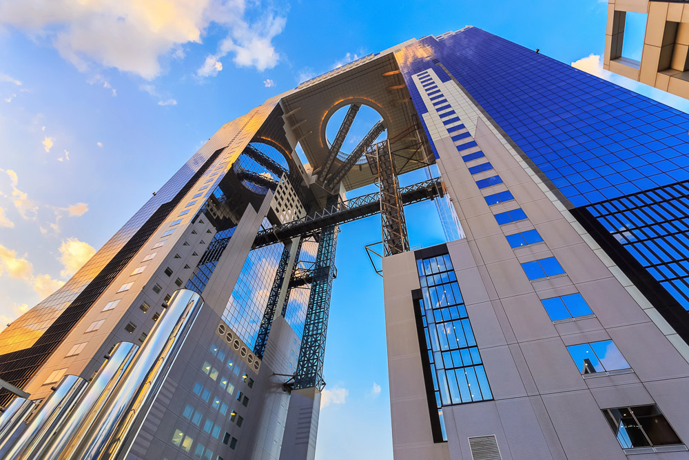 Umeda Sky Building visto de baixo, com torres espelhadas ligadas por estrutura suspensa.