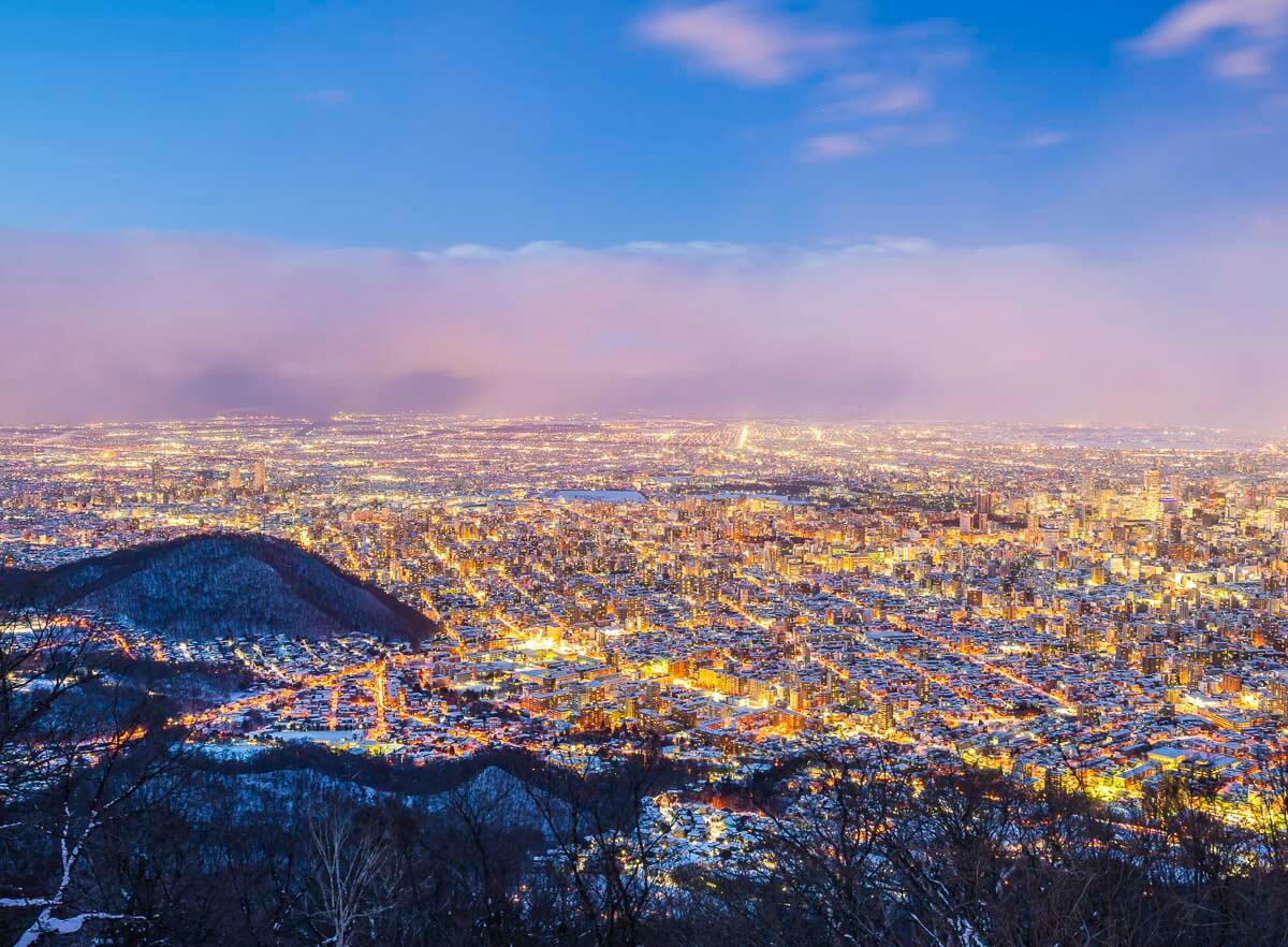 Vista noturna de Sapporo a partir do Monte Moiwa, com a cidade iluminada.