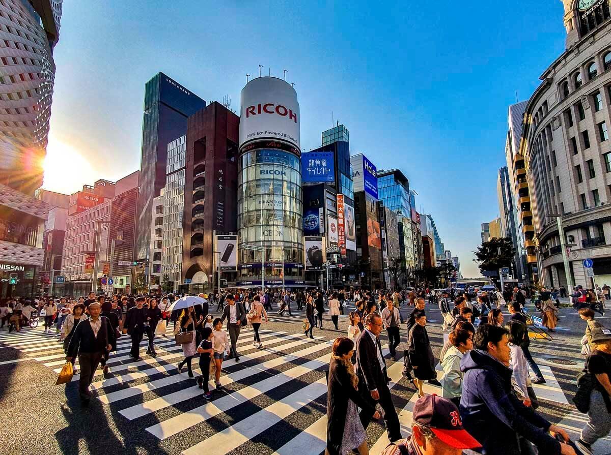 Cruzamento movimentado de Ginza, em Tokyo, com pedestres atravessando entre prédios comerciais modernos