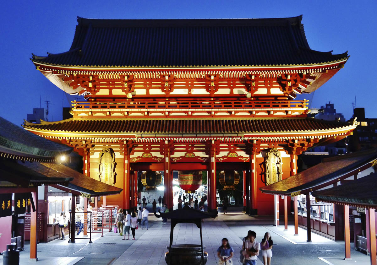 Portão iluminado do templo Senso-ji à noite, em Tokyo, com visitantes caminhando