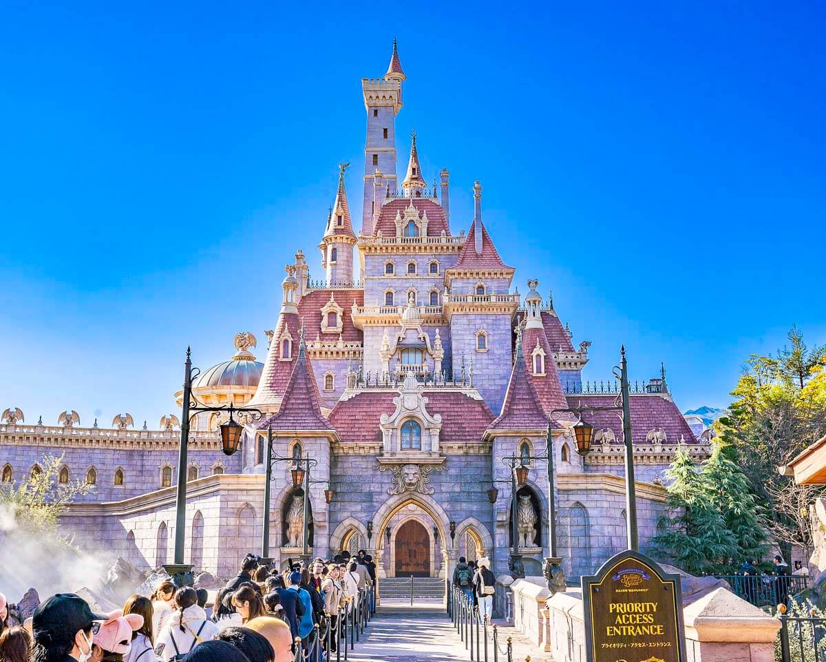 Castelo da Tokyo Disneyland com visitantes na entrada sob céu azul