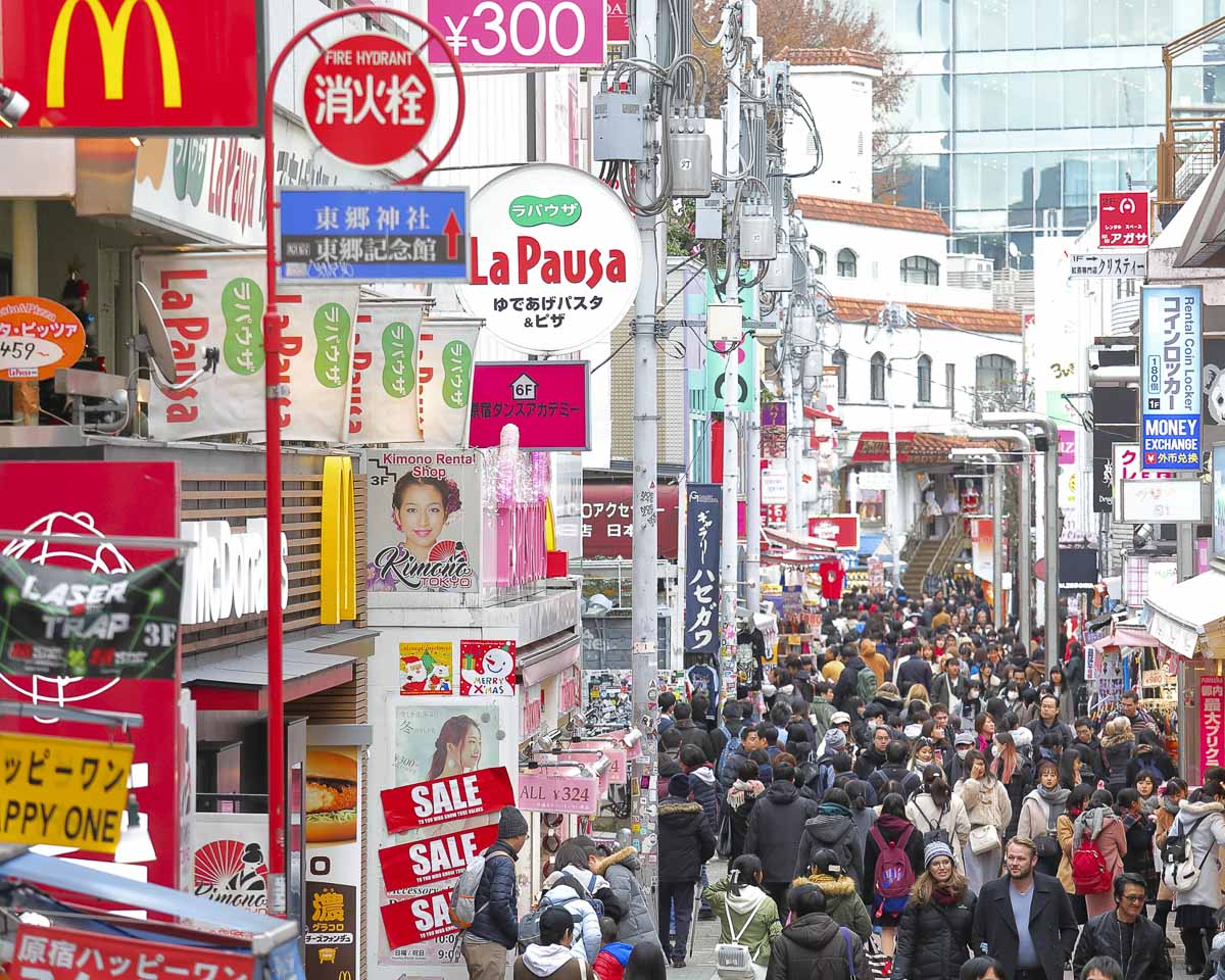 Rua movimentada de Harajuku, em Tokyo, com lojas e grande fluxo de pessoas