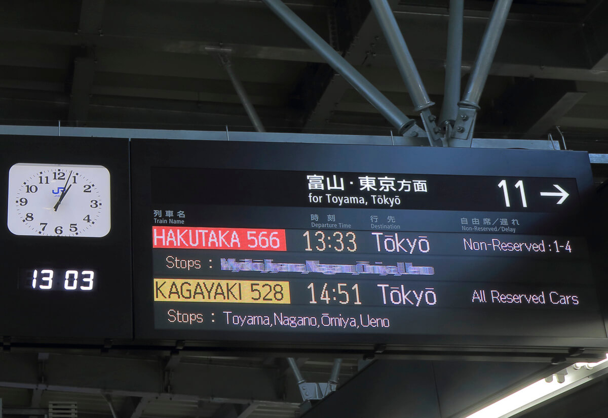 Painel eletrônico de estação japonesa mostrando horários de trens com destino a Tóquio.
