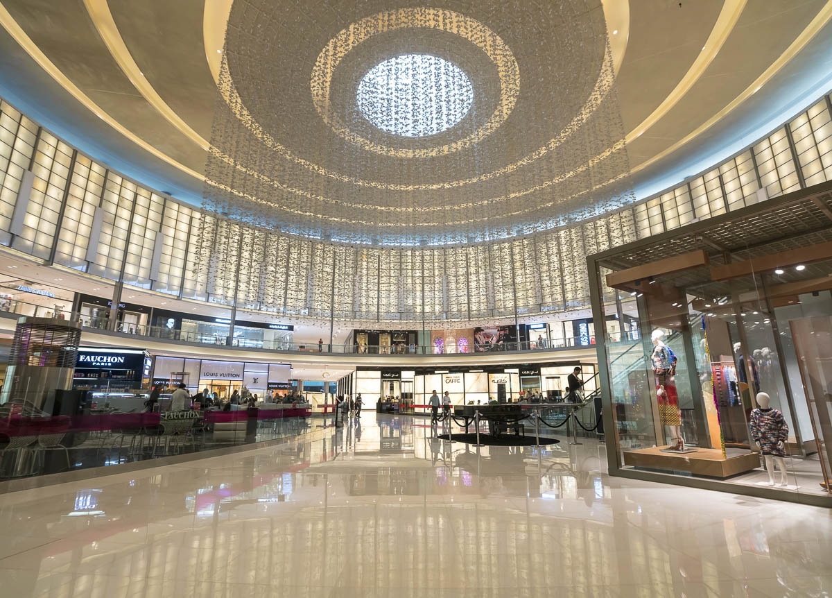 Interior do Dubai Mall com cúpula iluminada e lojas de luxo ao redor, em Dubai.