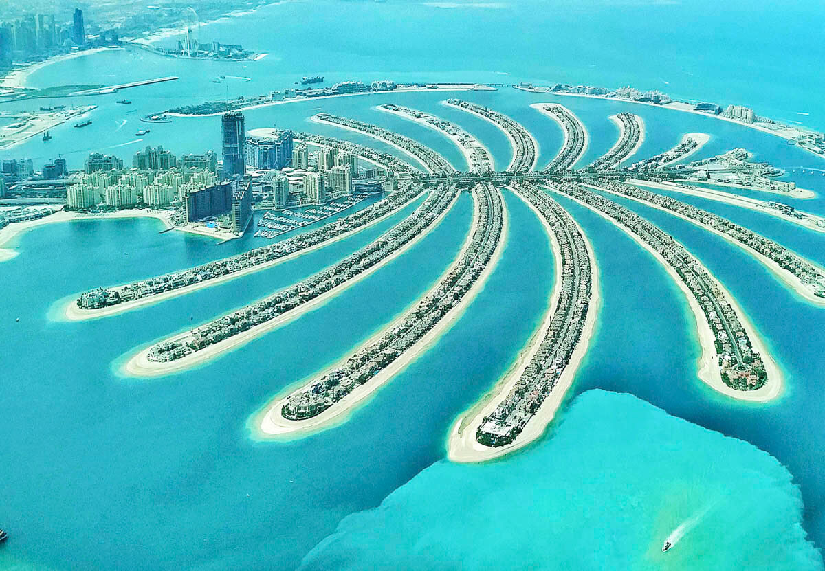 Vista aérea da Palm Jumeirah em Dubai com o formato de palmeira cercado por mar azul claro.