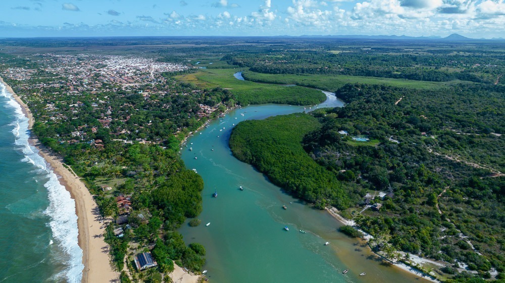 Vista aérea de Caraíva, com o rio serpenteando pelo manguezal e a praia longa ao lado do vilarejo.
