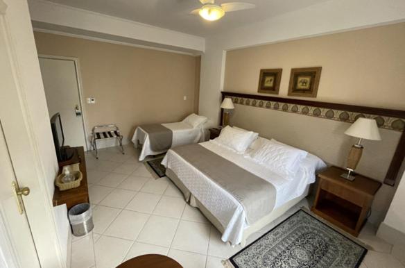 Quarto do Hotel Firenze em Serra Negra com cama de casal, cama de solteiro e decoração em tons claros