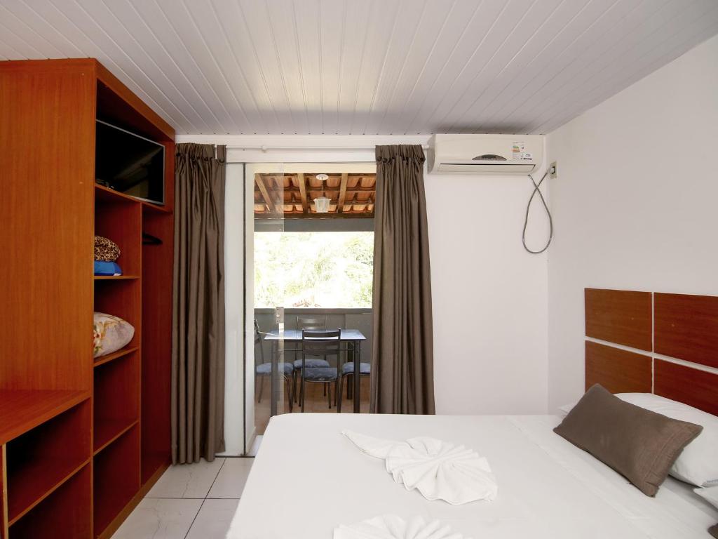 Quarto da Pousada Vale da Montanha em Serra Negra com cama de casal, armário aberto e varanda ao fundo