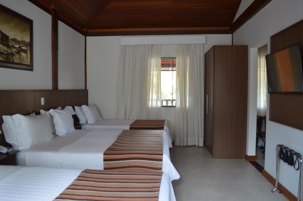 Quarto da Pousada Terê Parque em Teresópolis com três camas: uma de casal e duas de solteiro e decoração em madeira