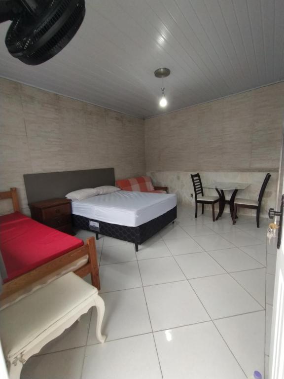 Quarto da Bertioga Litoral com cama de casal, sofá e pequena mesa com cadeiras