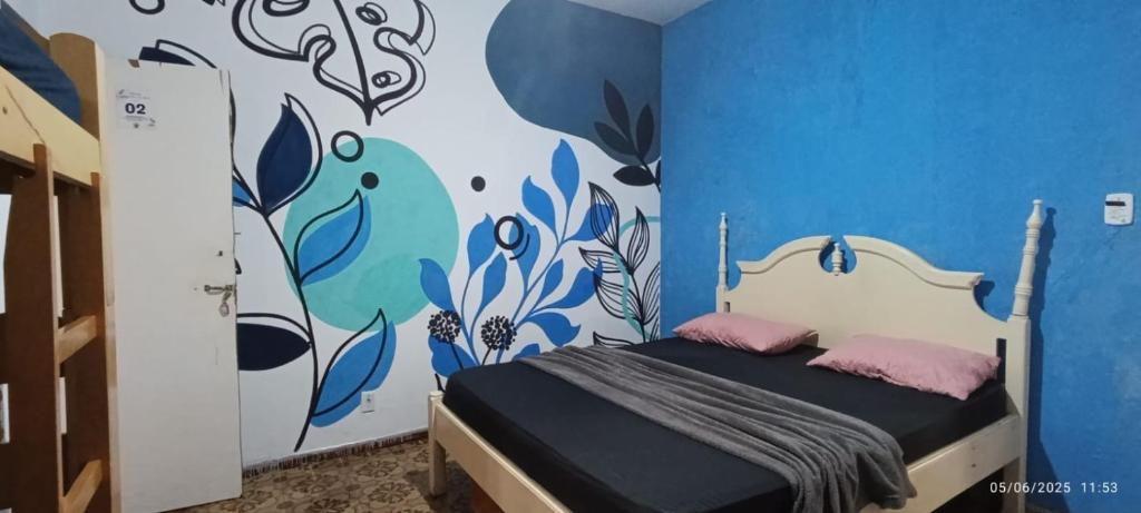 Quarto do Hostel Casarão do Surf com cama de casal e parede azul com grafismo