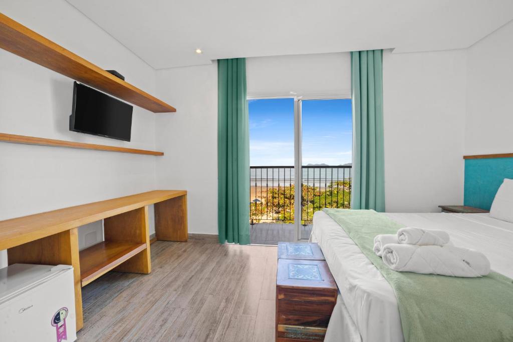 Quarto da Pousada Conca di Mare com cama de casal, TV na parede e varanda com vista para o mar