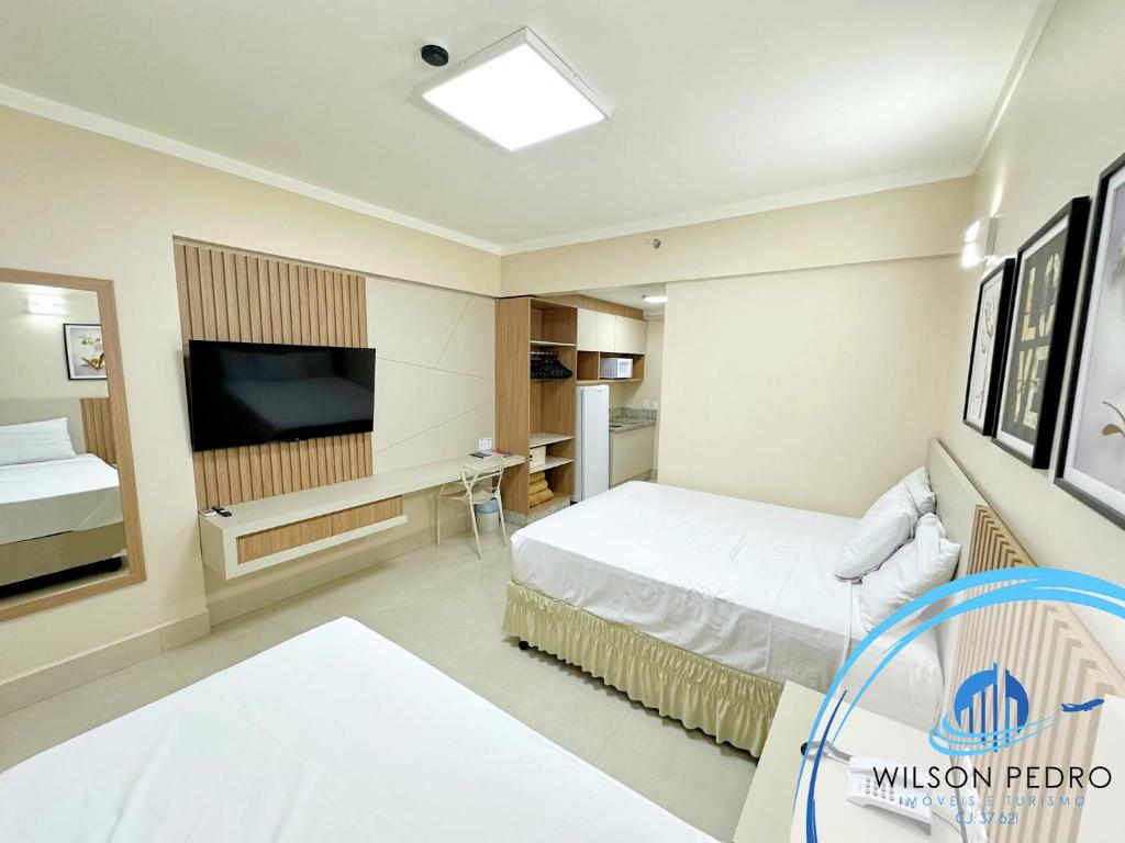 Quarto do Spazzio DiRoma em Caldas Novas com duas camas, TV e pequena cozinha ao fundo
