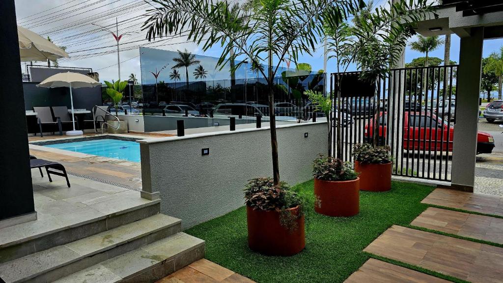 Área externa do Caraguá Flat em Caraguatatuba com piscina, espreguiçadeiras e jardim com vasos