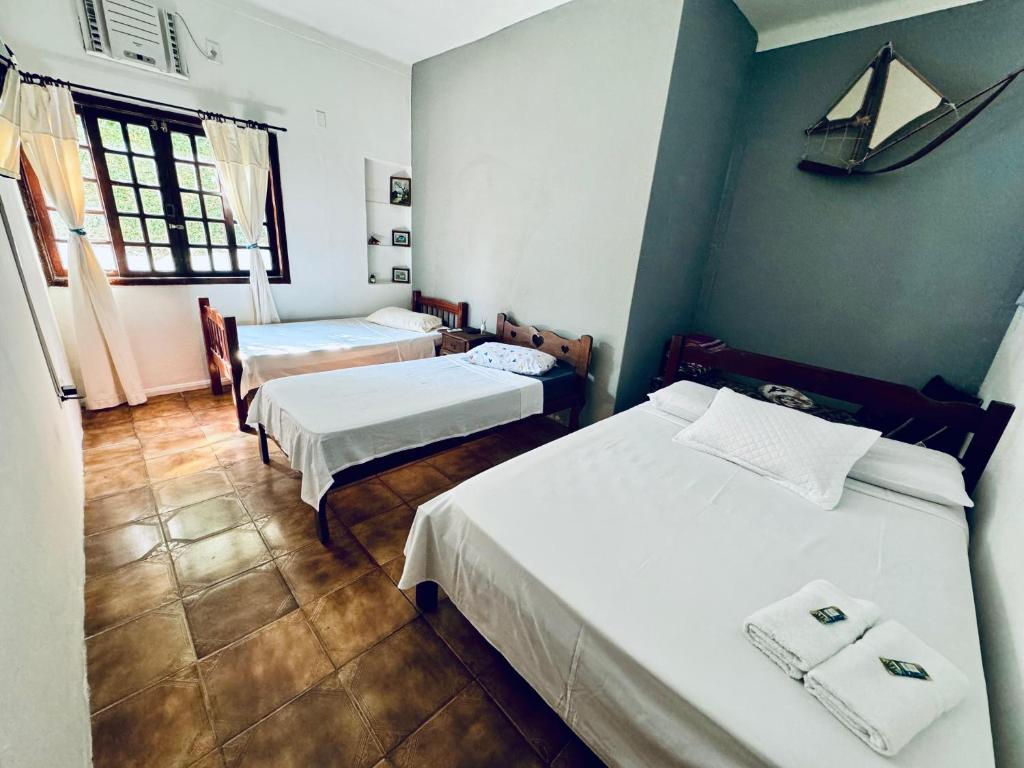 Quarto do Villavera Caraguá Centro em Caraguatatuba com três camas e janela com cortinas claras