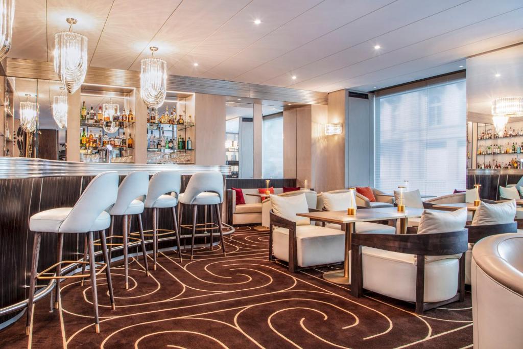 Bar do Hotel Bristol Genève com balcão iluminado e área de estar sofisticada