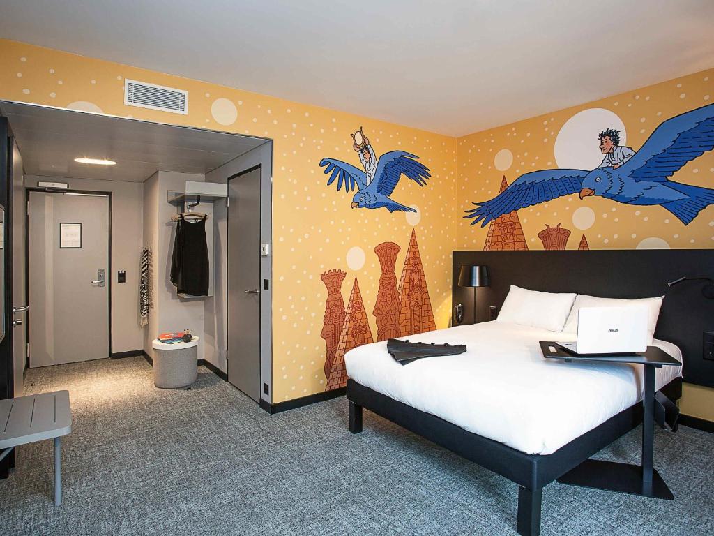 Quarto do ibis Styles Genève Carouge com parede ilustrada e cama de casal