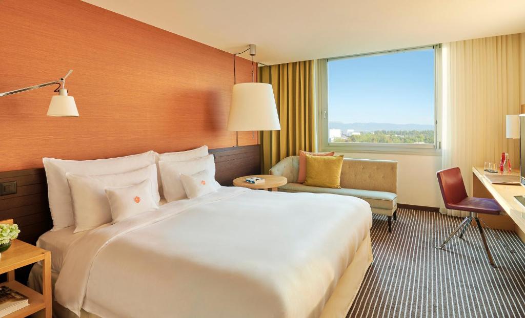 Quarto do InterContinental Genève com cama king, mesa de trabalho e janela ampla