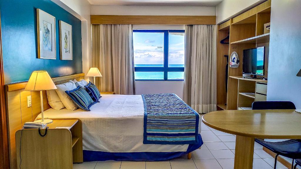 Quarto do Reymar Hotel Maceió com cama de casal, vista para o mar e mobiliário em madeira