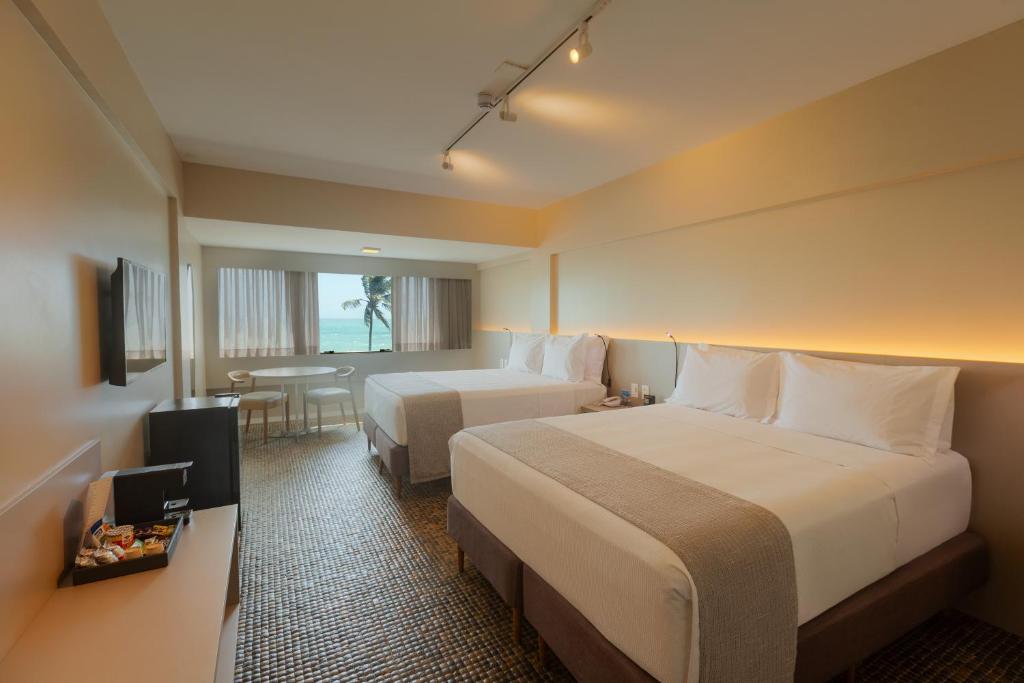 Quarto do Ritz Lagoa da Anta Hotel and Spa em Maceió com duas camas de casal, iluminação indireta e janela com vista para o mar