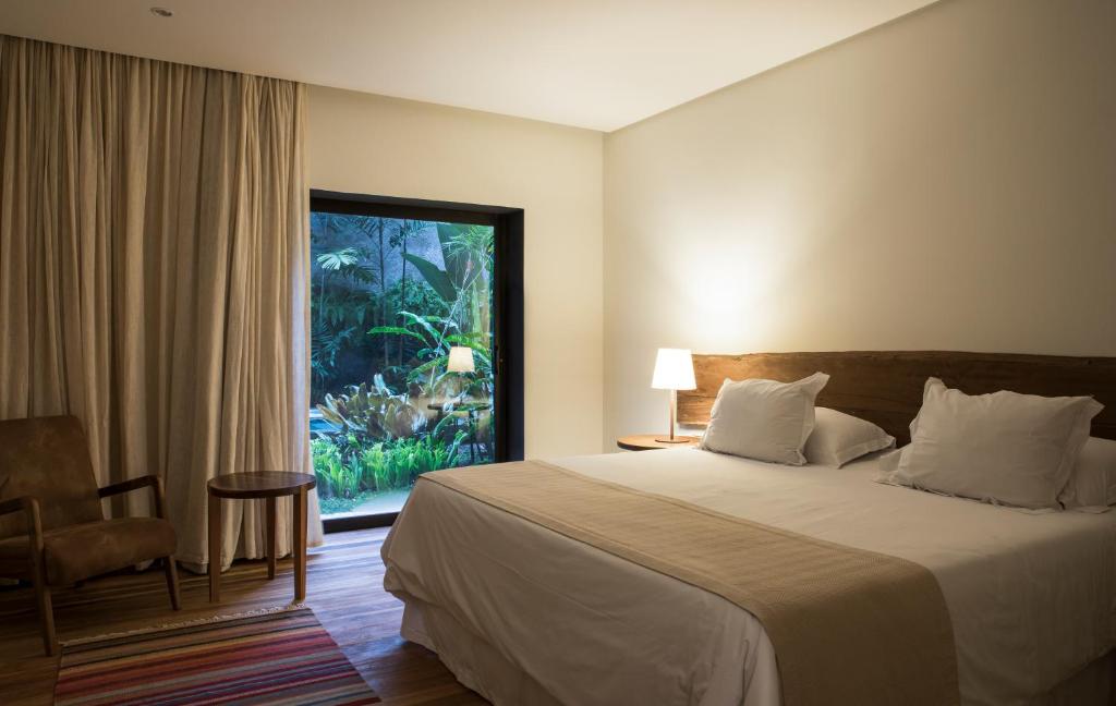 Quarto do Hotel Villa Amazônia em Manaus com cama de casal e porta de vidro com vista para jardim
