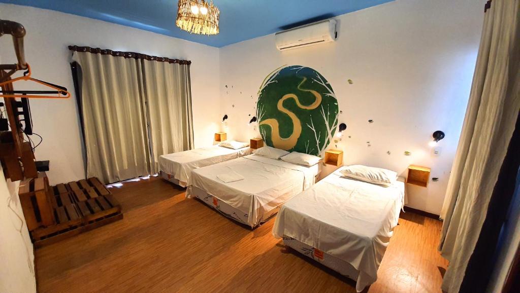 Quarto do Local Hostel Manaus com três camas de solteiro e parede com arte colorida