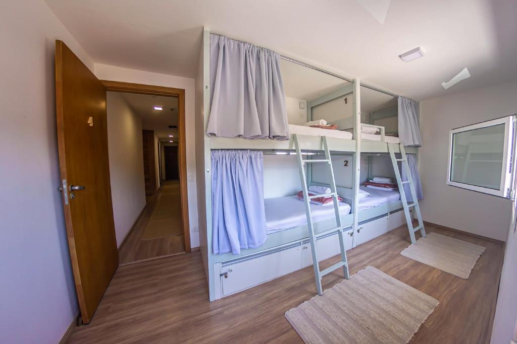 Quarto compartilhado com beliches, cortinas individuais e escadas em ambiente claro