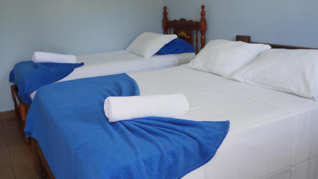 Quarto simples com cama de casal e cama de solteiro, roupas de cama brancas e mantas azuis