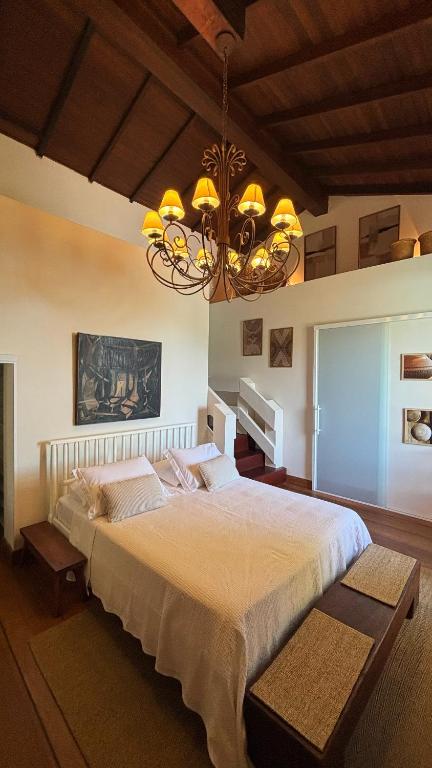 Quarto elegante com cama de casal, lustre decorativo e teto de madeira