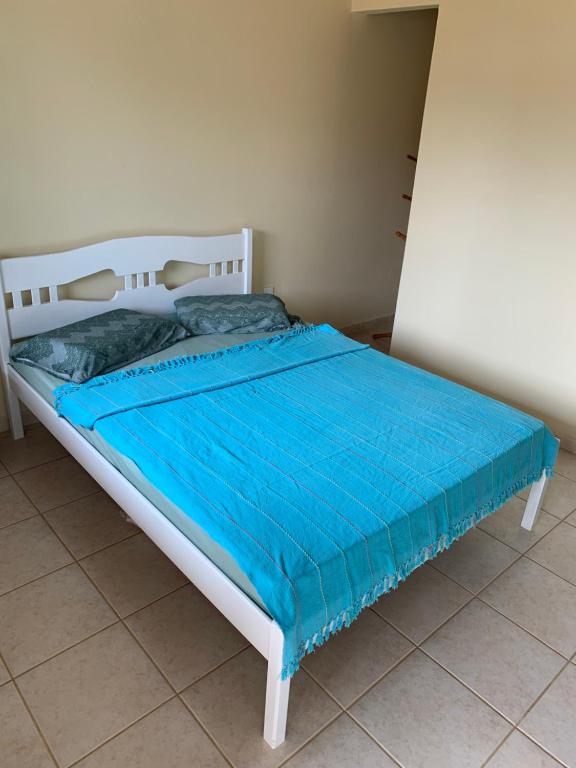 Quarto compacto com cama de casal, colcha azul e paredes claras