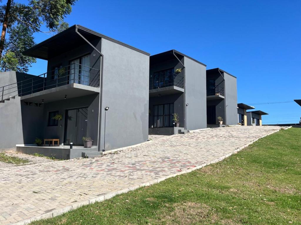 Área externa dos São Roque Chalés com unidades modernas cinza, varandas e caminho pavimentado em meio ao gramado