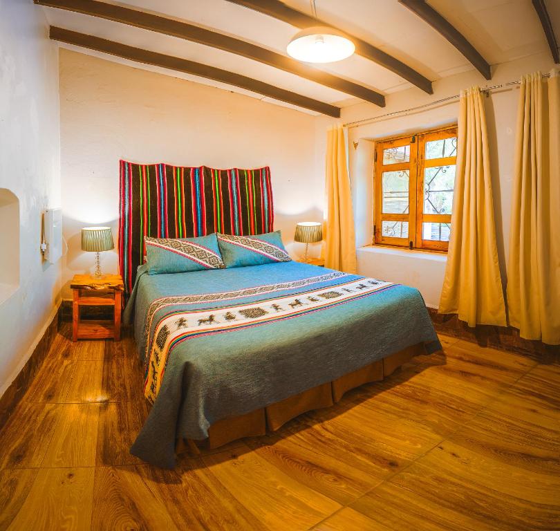 Quarto do Ckoi Atacama Lodge no Atacama com cama de casal, manta colorida e janela de madeira