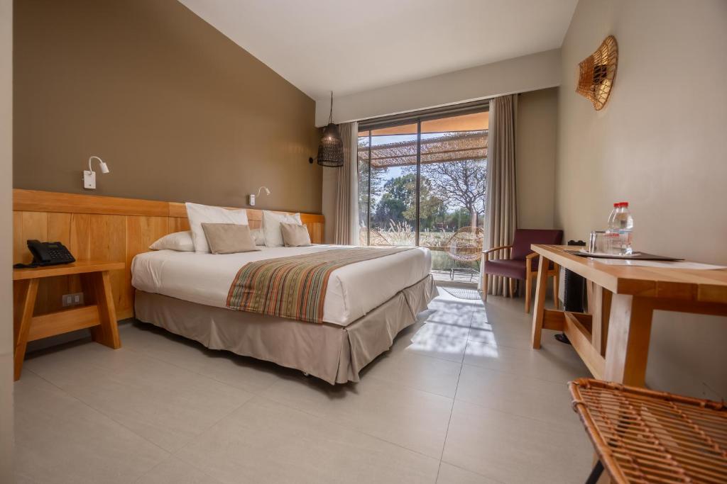 Quarto do Hotel La Casa de Don Tomás no Atacama com cama de casal e porta de vidro para área externa