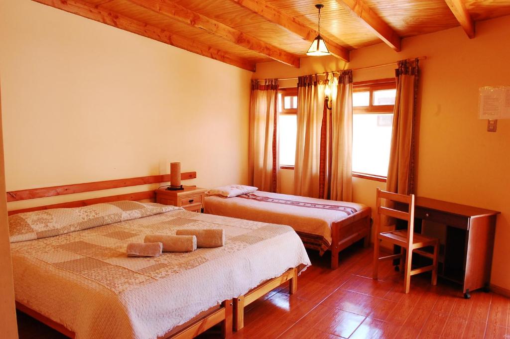 Quarto do Quechua Hotel no Atacama com cama de casal, cama de solteiro e teto de madeira