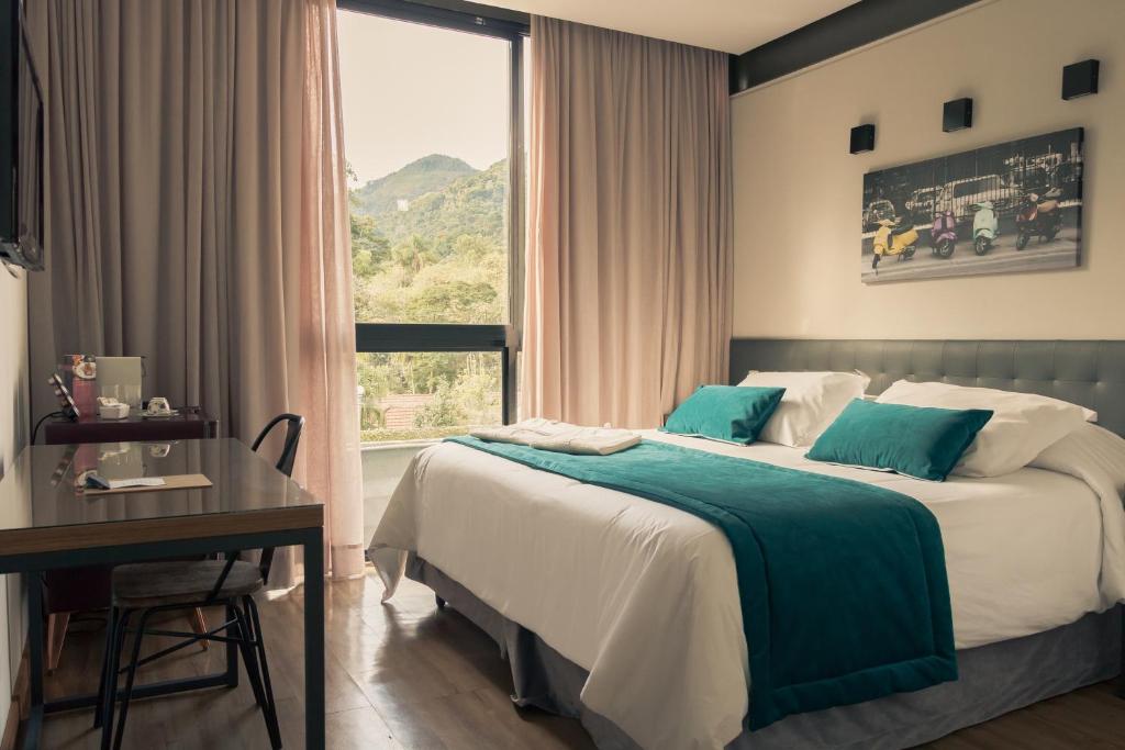 Quarto da Casa Rosa Hotel Boutique em Petrópolis com cama de casal e janela com vista para montanhas