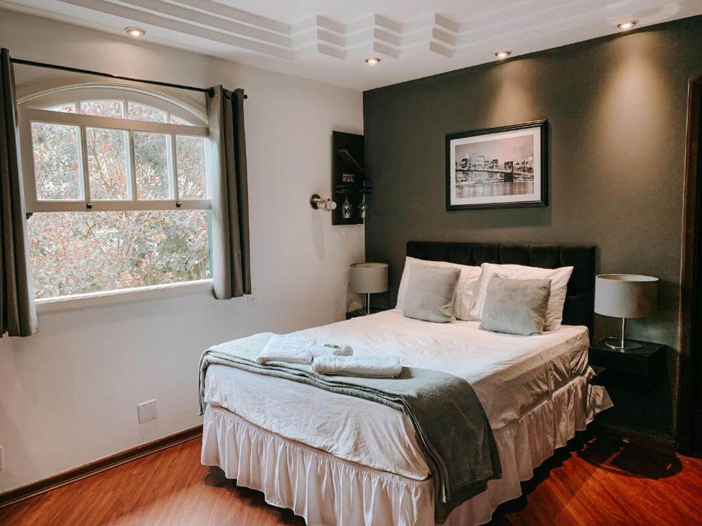 Quarto da Pousada Vale Valparaíso Inn em Petrópolis com cama de casal e parede escura decorada