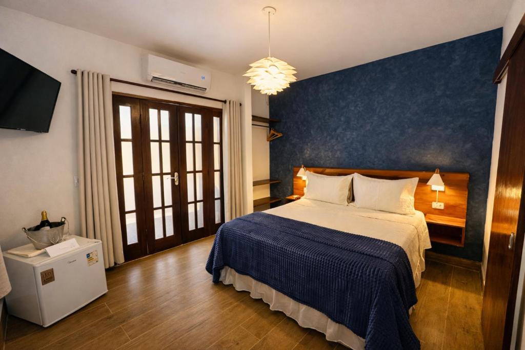 Quarto da Pousada Arriba Pipa em Pipa com cama de casal, parede azul e portas de madeira