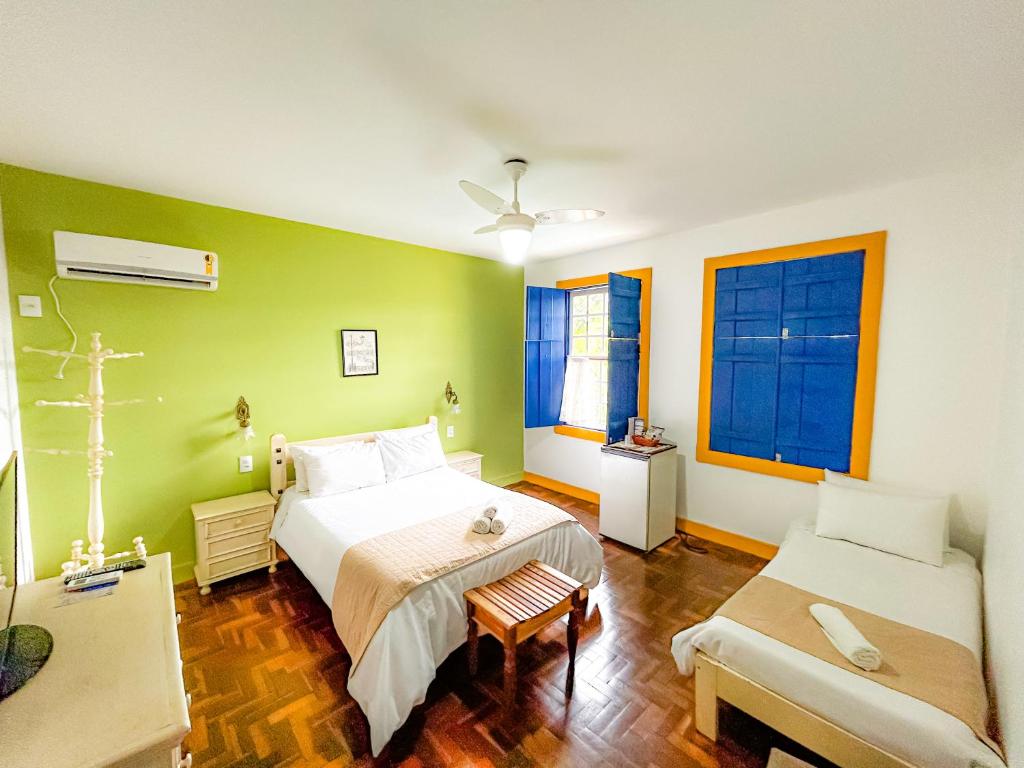 Quarto da Pousada Casarão em São João del Rei com cama de casal, cama de solteiro e janelas azuis