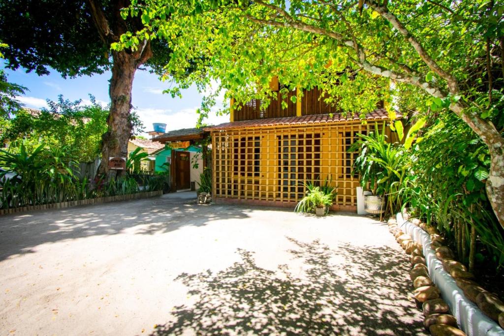 Área externa da Pousada Pôr do Sol Trancoso em Trancoso com jardim, árvores e fachada rústica