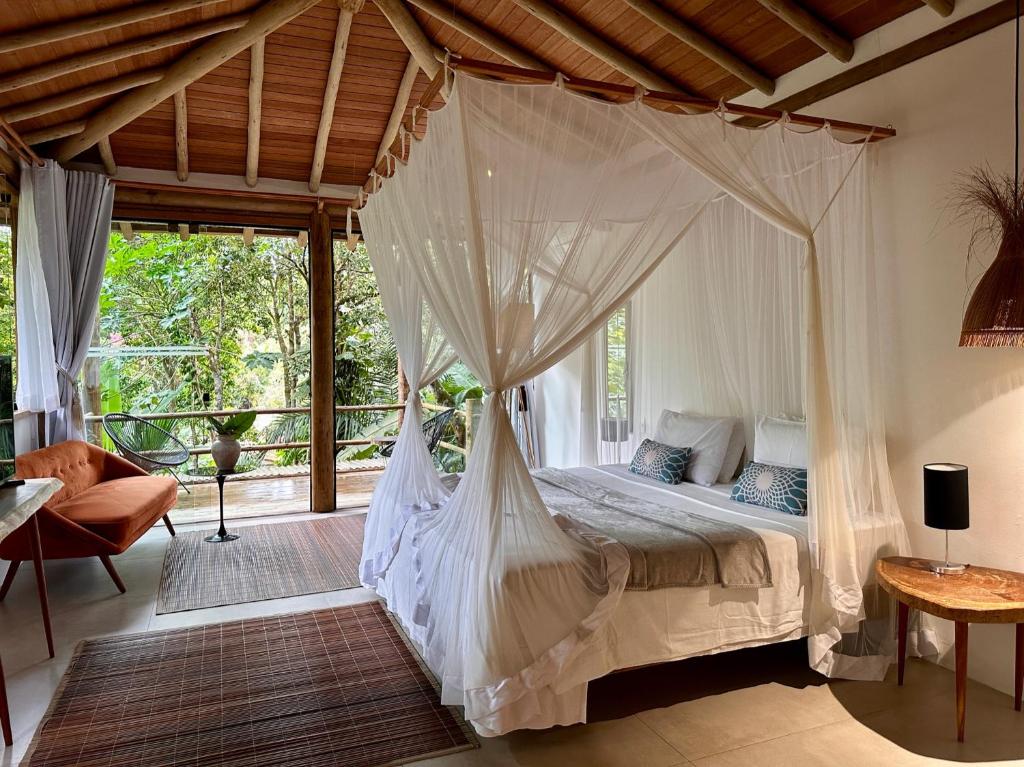 Quarto da Soleluna Casa Pousada em Trancoso com cama com dossel e varanda com vista para natureza