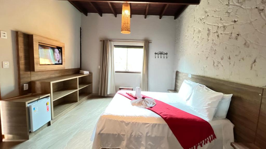 Quarto da Pousada Flor de Pequi na Serra do Cipó com cama de casal, painel de TV e decoração rústica