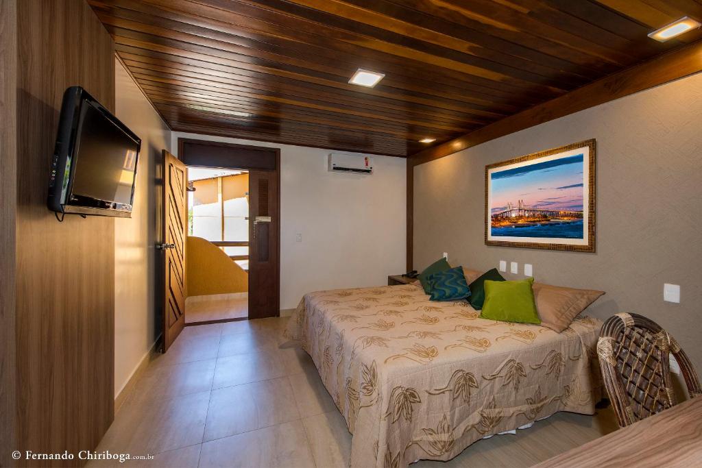 Quarto do Natal Dunnas Hotel em Natal com cama de casal, TV e decoração simples em tons neutros