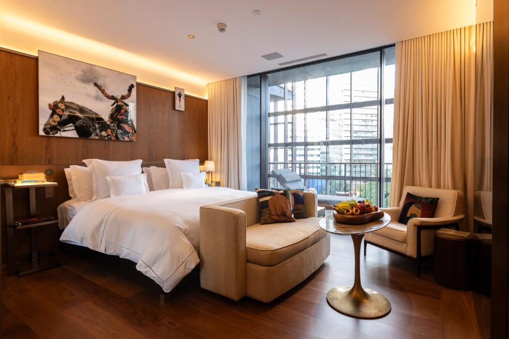 Quarto do Rosewood São Paulo com cama ampla, sofá e varanda com vista urbana