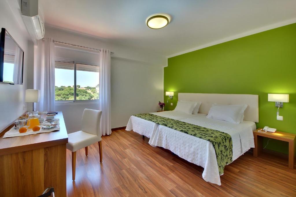 Quarto do Hotel Zodiaco no Algarve com parede verde e cama de casal