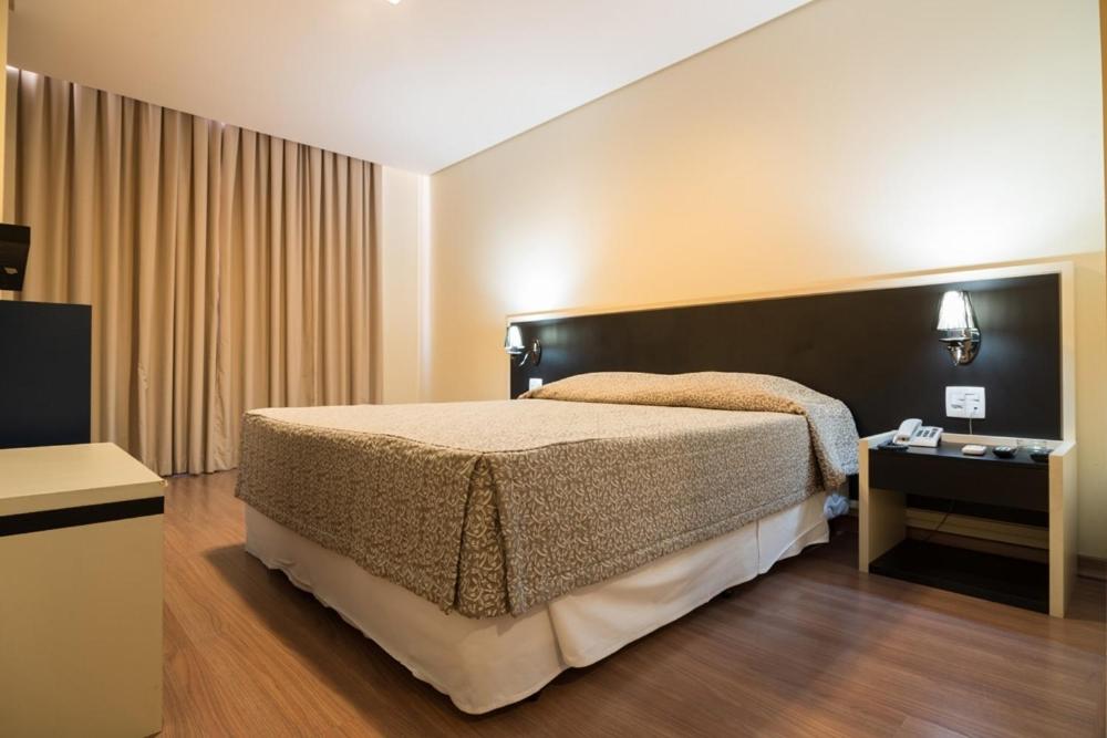 Quarto do Hotel Financial em Belo Horizonte com cama de casal e iluminação suave