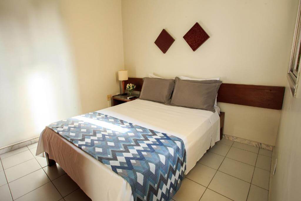 Quarto do Pampulha Flat em Belo Horizonte com cama de casal e manta azul