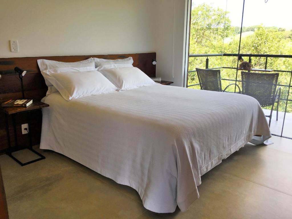 Quarto do Latitude Lodge em Cunha com cama de casal e varanda com cadeiras e vista para natureza